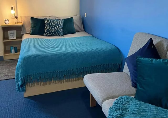 Bed with blue blanket pillows and sofa bedroom at Nottingham Two in Nottingham Student Accommodation