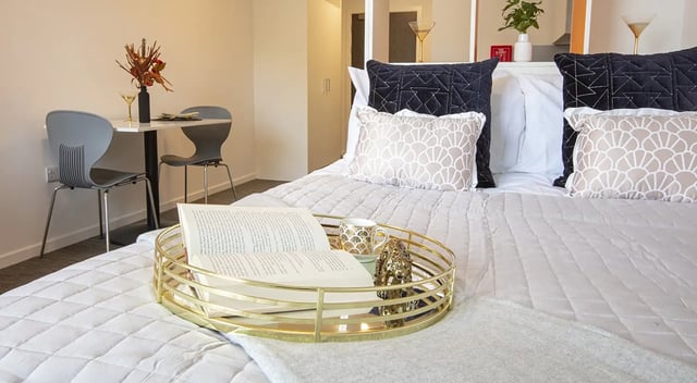 Bed with tray table chair and decorative pillows bedroom at Fraser Studios in Aberdeen Student Accommodation