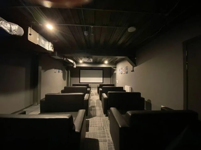 Rows of dark couches face a projector screen cinema room at Fraser Studios in Aberdeen Student Accommodation
