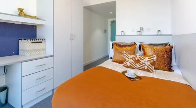 Bed with orange blanket study desk and closet bedroom at The Union Leamington in Leamington Spa Student Accommodation