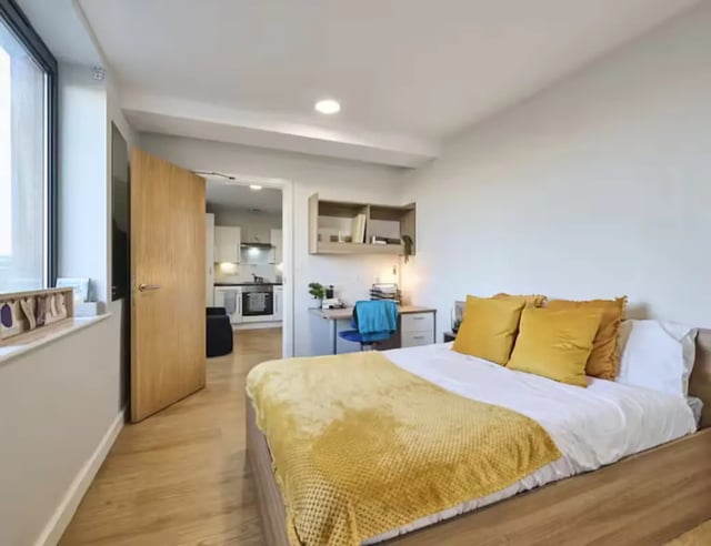 Bed with yellow pillows study area kitchen bedroom at The Summit Leicester in Leicester Student Accommodation
