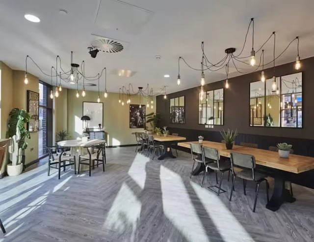 Modern common room with tables chairs and plants at York House in Nottingham Student Accommodation