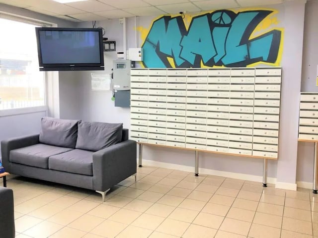 Gray couch mailboxes wall art common area at Horton House Bradford in Bradford Student Accommodation