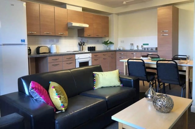 Black leather couch dining table kitchen living room at Horton House Bradford in Bradford Student Accommodation