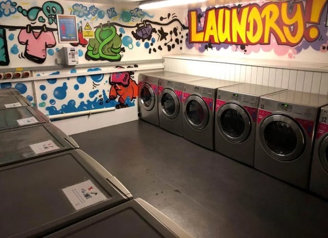 Washing machines and dryers with graffiti decor laundry room at Horton House Bradford in Bradford Student Accommodation