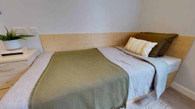 Bed with green throw and pillows bedroom at iQ Student Quarter in Salford Student Accommodation