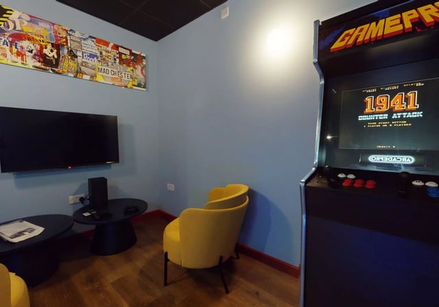 Arcade machine TV and yellow chair playing area at iQ Student Quarter in Salford Student Accommodation