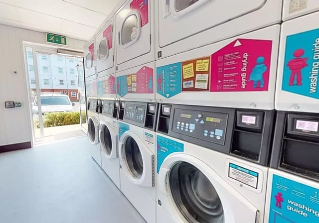 Row of stacked washing machines with digital panels Laundry room at iQ Student Quarter in Salford Student Accommodation