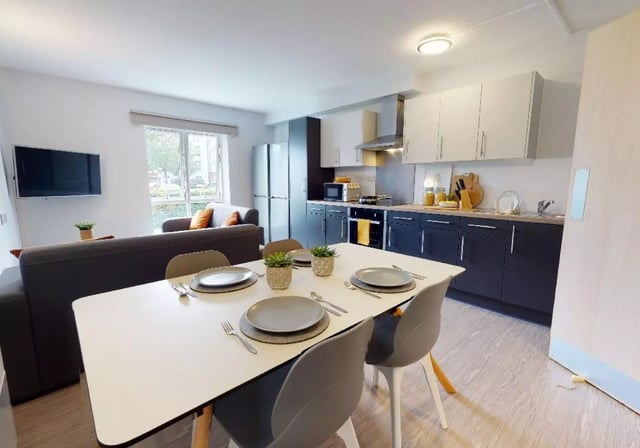 Table with place settings and kitchen area living room at iQ Student Quarter in Salford Student Accommodation