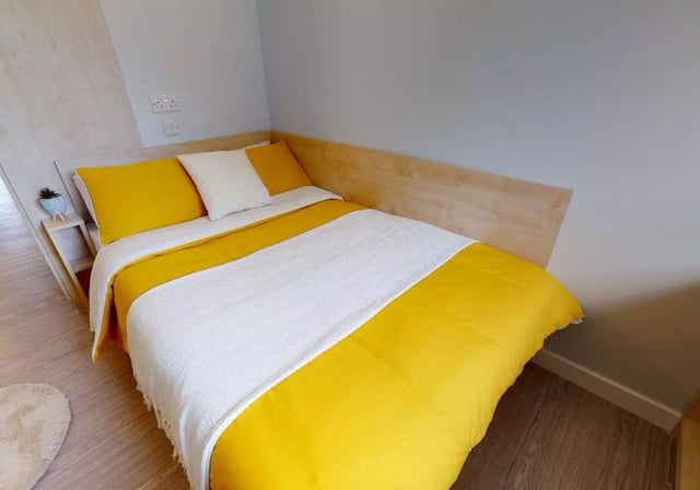 Bed with yellow duvet white blanket and pillows bedroom at iQ Student Quarter in Salford Student Accommodation