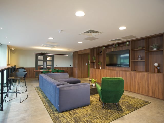 Blue sofa green chair TV built-in shelving living room at Straits Garden in Egham Student Accommodation