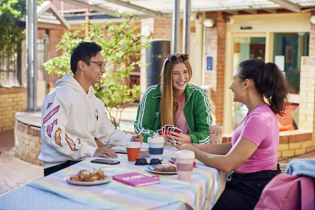 Students playing cards at outdoor table communal area exterior at Boundary x Scape in Sydney Student Accommodation
