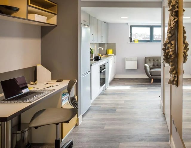 Desk chair laptop kitchen area and living area at The Glassworks - Leeds in Leeds Student Accommodation