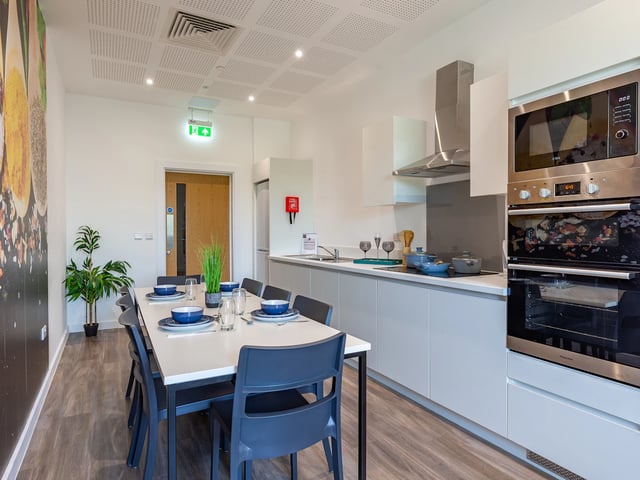 Dining table with place settings and kitchen area kitchen at Hill View Place in Exeter Student Accommodation
