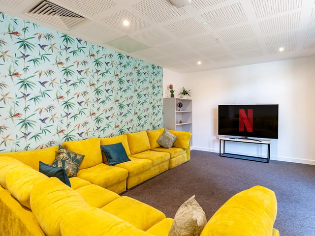 Yellow sectional sofa and TV living room at Hill View Place in Exeter Student Accommodation