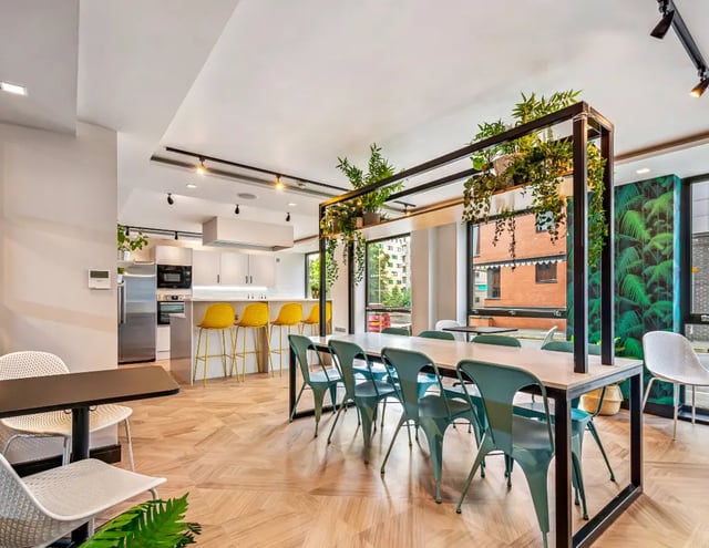 Modern communal kitchen and dining area with plants. at The Edge - Leeds in Leeds Student Accommodation