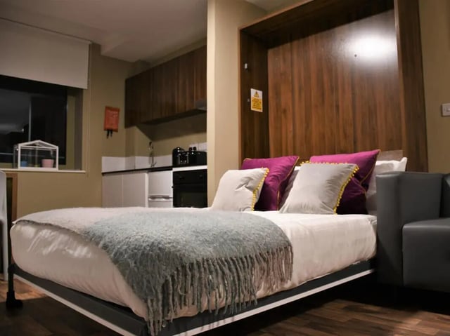Bed with plush pillows kitchen area studio apartment at Pembroke Studios in Liverpool Student Accommodation