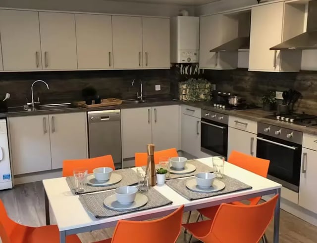 Dining table with orange chairs kitchen area. at Solly House - Central Place in Sheffield Student Accommodation