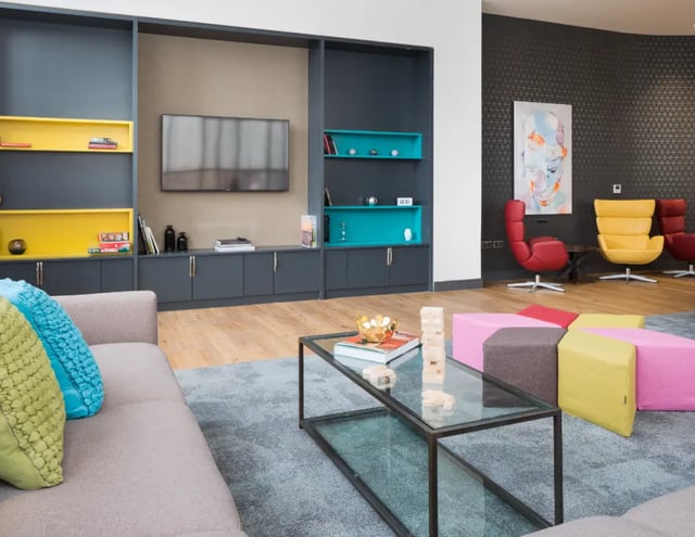 Sofa coffee table TV shelves colorful chairs living room at The Ascent in Liverpool Student Accommodation