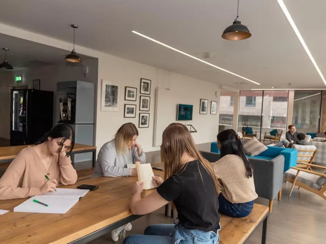Students study at wooden tables communal living room at Powis Place in Aberdeen Student Accommodation