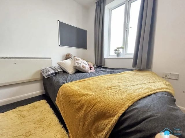 Bed with yellow blanket and pillows blackboard and radiator bedroom at Rochester Student Village in Rochester Student Accommodation