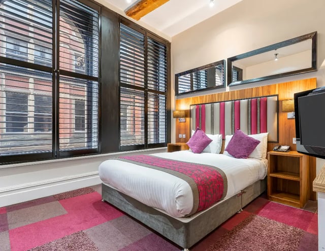 Bed with purple pillows, TV, and mirrors Bedroom at IconInc Manchester City in Manchester Student Accommodation