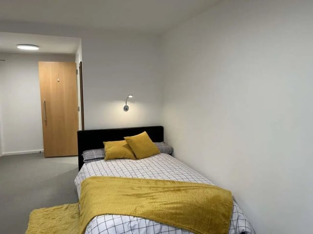 Bed with yellow pillows and throw carpet bedroom at Nebula in Sheffield Student Accommodation