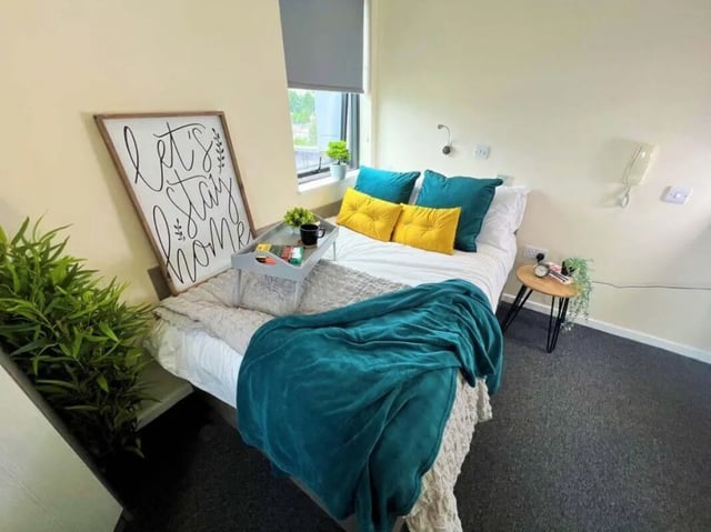 Bed with teal blanket and decorative sign bedroom at Stratus in Sheffield Student Accommodation