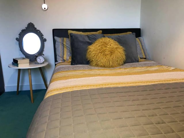 Bed with pillows mirror alarm clock books bedroom at Plato House in Liverpool Student Accommodation