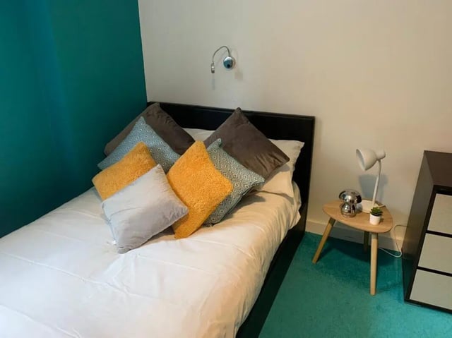 Bed with colorful pillows small bedside table bedroom at Plato House in Liverpool Student Accommodation