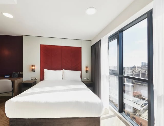 Bed with white linens red headboard desk phone bedroom at IconInc Newcastle City in Newcastle Upon Tyne Student Accommodation