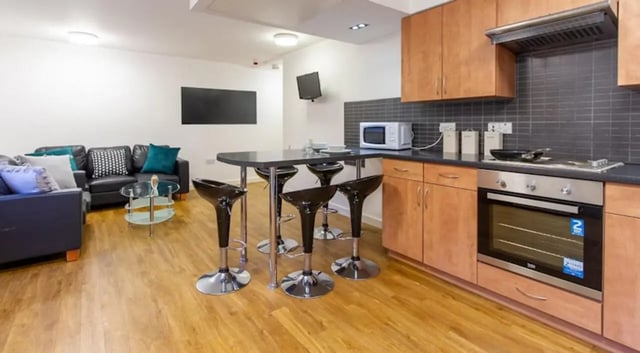 Leather couch coffee table bar stools kitchen living room at Exeter One in Exeter Student Accommodation