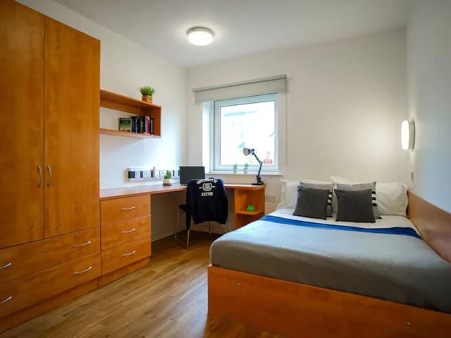 Bed desk wardrobe and bookshelf student bedroom at Exeter One in Exeter Student Accommodation