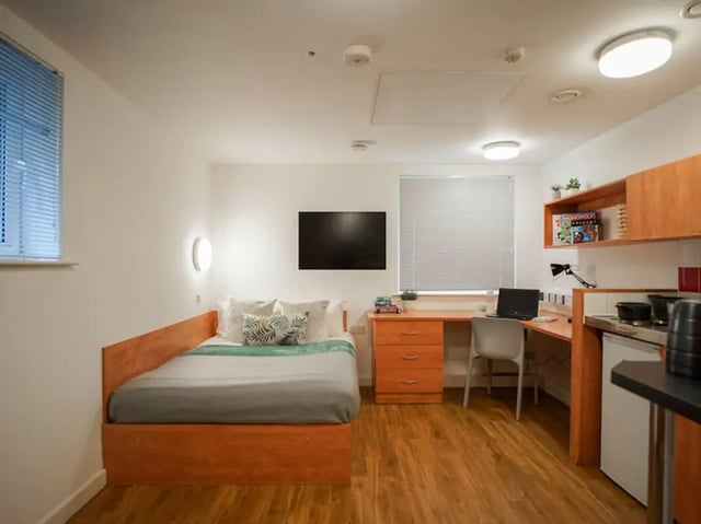 Bed desk chair kitchen area studio apartment at Exeter One in Exeter Student Accommodation