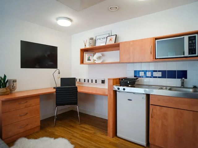 Desk chair laptop TV microwave sink stovetop kitchen at Exeter One in Exeter Student Accommodation