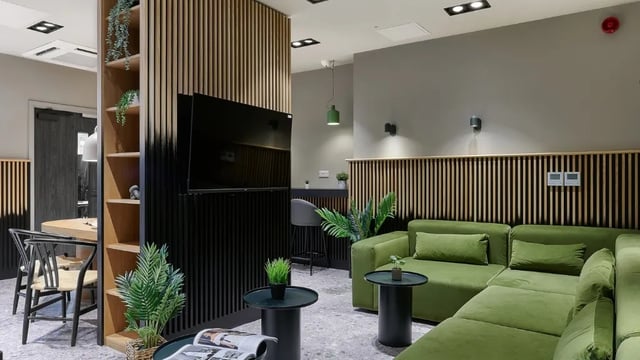Green sectional sofa bar stools and dining set living room at The Helix in London Student Accommodation