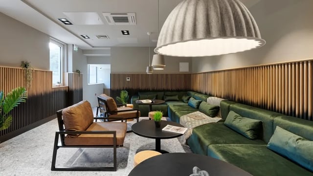 Green sectional sofa brown chairs tables living room at The Helix in London Student Accommodation