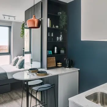 Bed and kitchen counter with stools interior at ARK Canary Wharf in London Student Accommodation