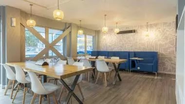 Tables chairs and blue booths communal area at iQ Broderick House in Birmingham Student Accommodation