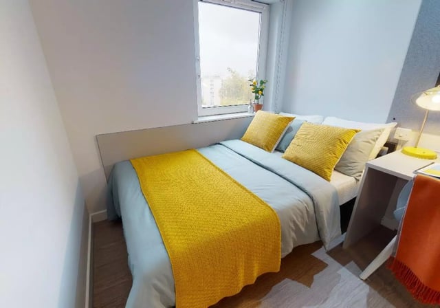 Bed with yellow pillows desk and lamp bedroom at iQ Broderick House in Birmingham Student Accommodation