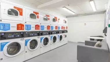 Washing machines dryers and seating area laundry room at iQ Broderick House in Birmingham Student Accommodation