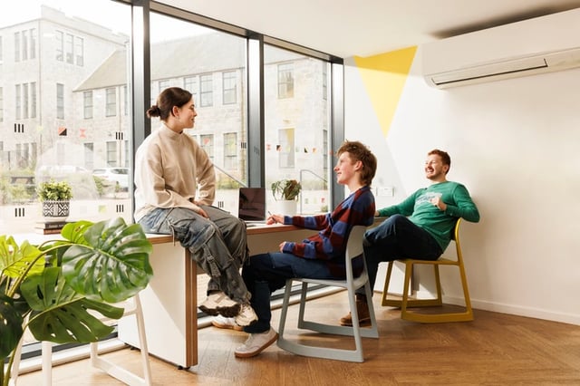 Students by desk and plants common area living room at Causeway View in Aberdeen Student Accommodation