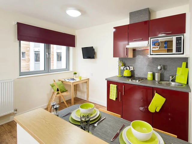 Red cabinets microwave sink table and chairs kitchen at Quebec House in Kingston Upon Thames Student Accommodation