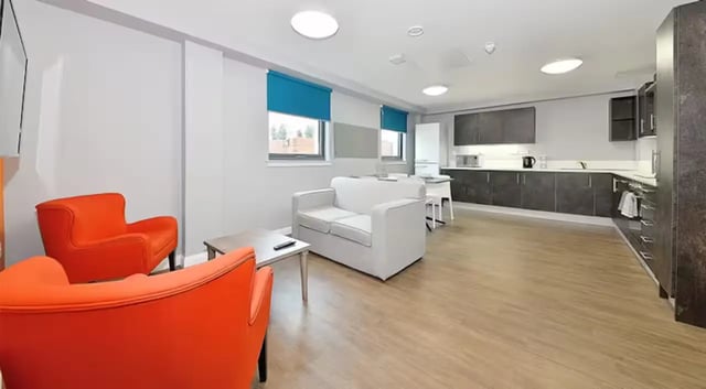 Orange chairs white sofa kitchen area living room at The Mill House in Edinburgh Student Accommodation