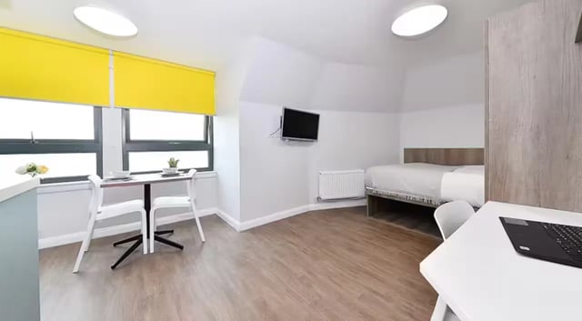Bed desk table yellow blinds TV bedroom at The Mill House in Edinburgh Student Accommodation