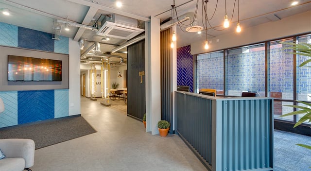 Reception desk with textured wall and TV lounge at The Tramshed in Preston Student Accommodation