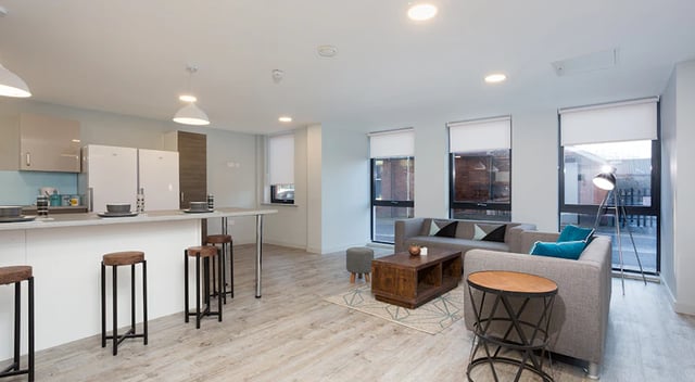 Kitchen with breakfast bar and living room with sofas at The Tramshed in Preston Student Accommodation