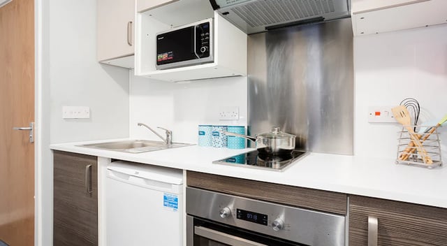 Kitchen counter with microwave sink stove and utensils kitchen at The Tramshed in Preston Student Accommodation