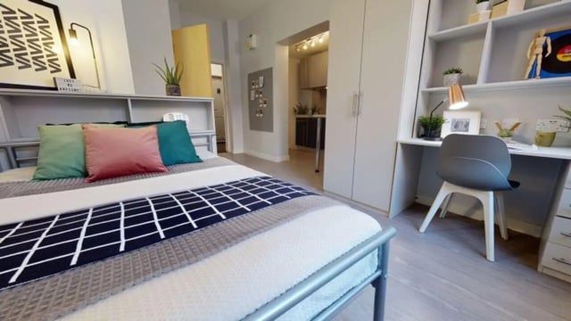 Bed desk chair storage and kitchen visible bedroom at iQ Studios 51 in Birmingham Student Accommodation