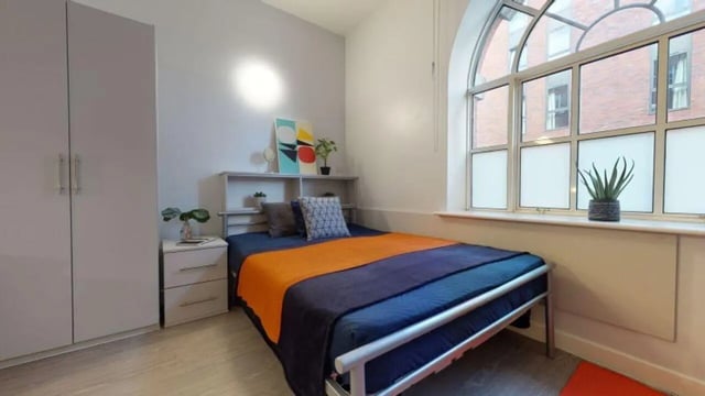 Bed bedside cabinet wardrobe art and plant bedroom at iQ Studios 51 in Birmingham Student Accommodation
